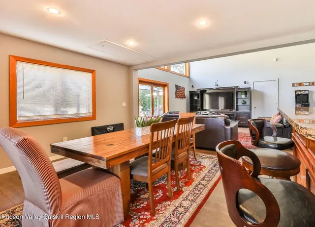 a living room with furniture two large windows and a dining table