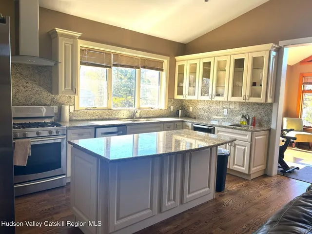 a kitchen with kitchen island granite countertop a sink stove and cabinets