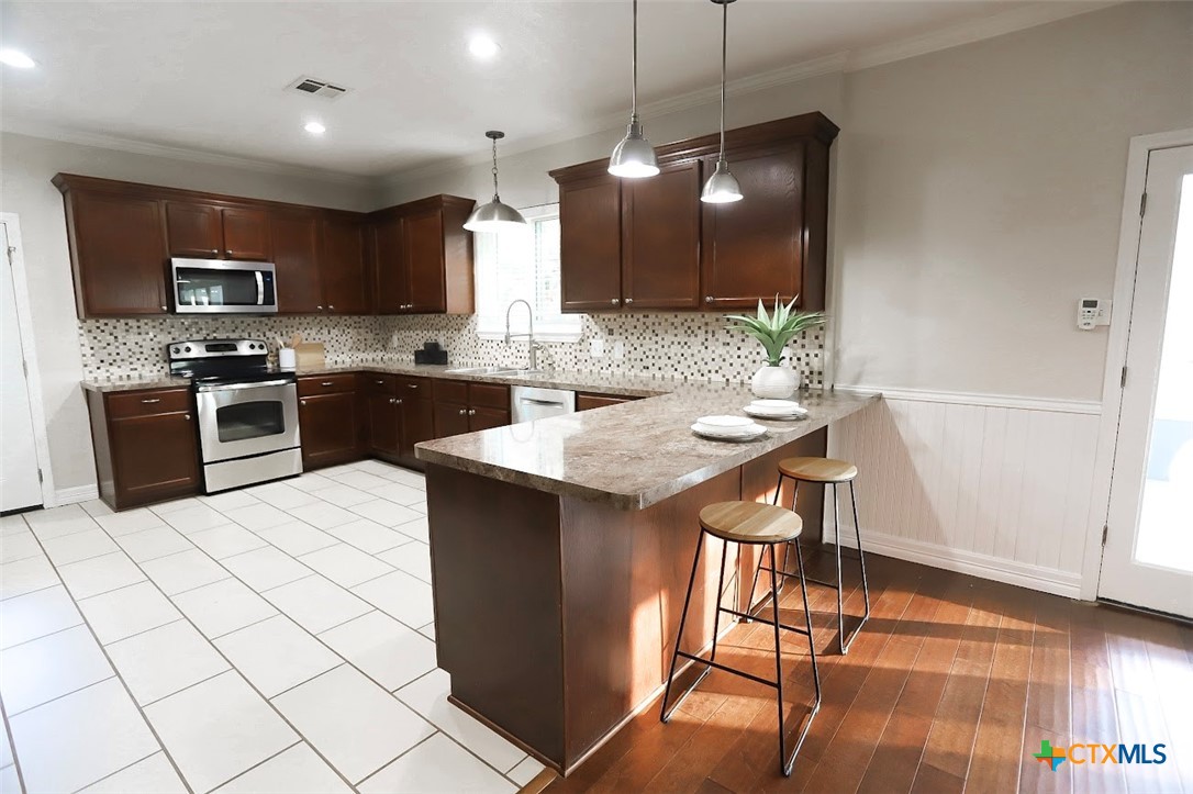 1701 Sulpher Wells Road Salado, TX 76571 - Photo 18 of 34 a kitchen with stainless steel appliances kitchen island granite countertop a sink wooden cabinets and a granite counter tops