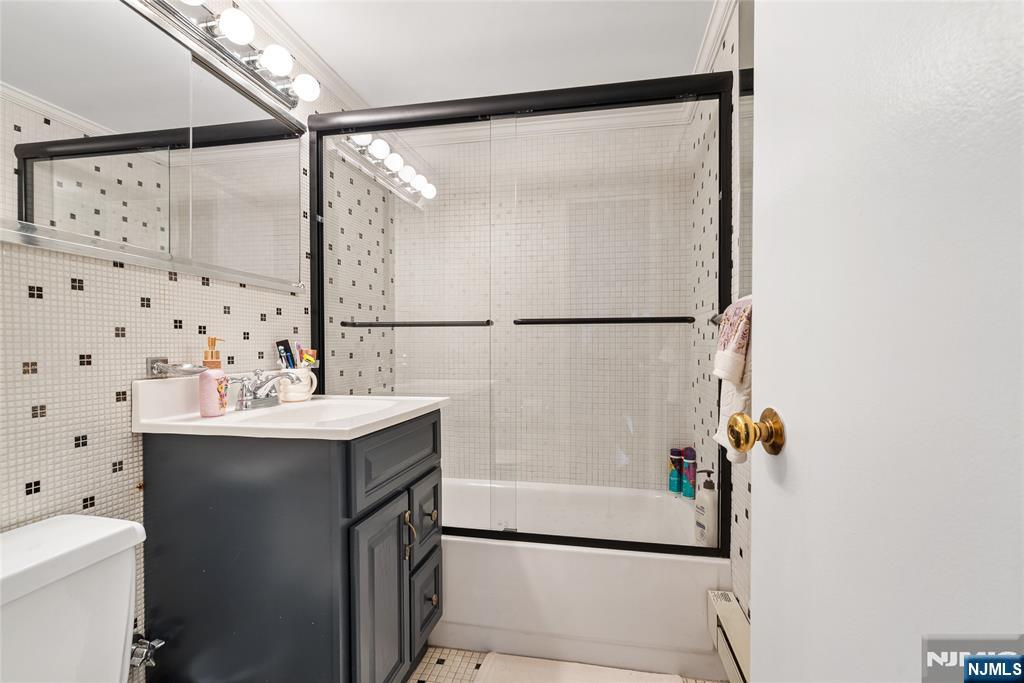 301 Beech Street, Unit 2B Hackensack, NJ 07601 - Photo 16 of 21 a bathroom with a sink and mirror with bathtub