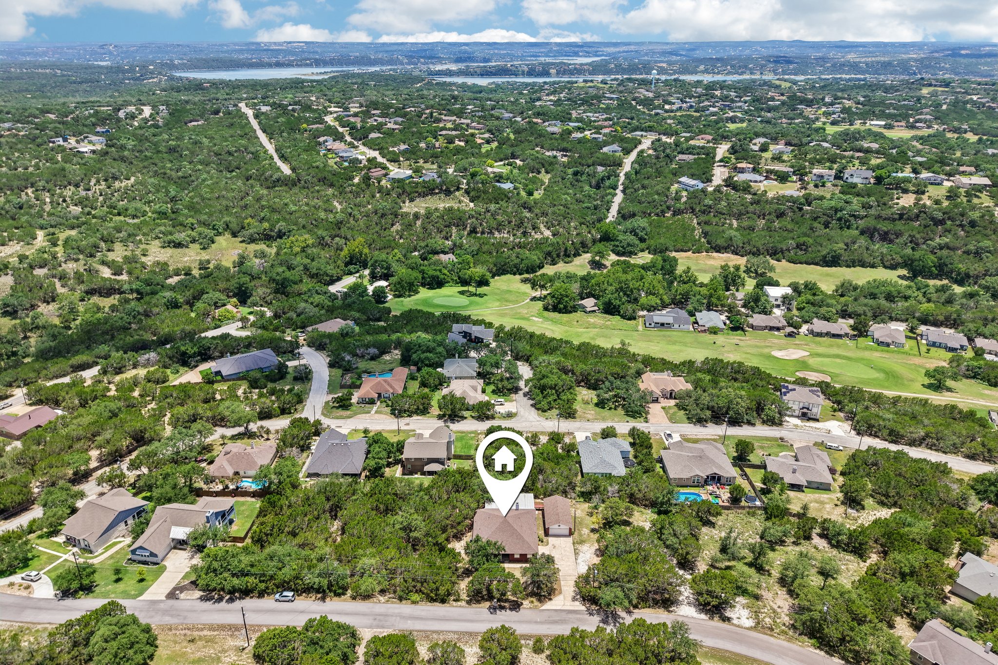 20609 Bridle Path Road Lago Vista, TX 78645 - Photo 24 of 30 An aerial perspective reveals a charming residential neighborhood enveloped by verdant trees, with glimpses of a golf course and a distant body of water.
