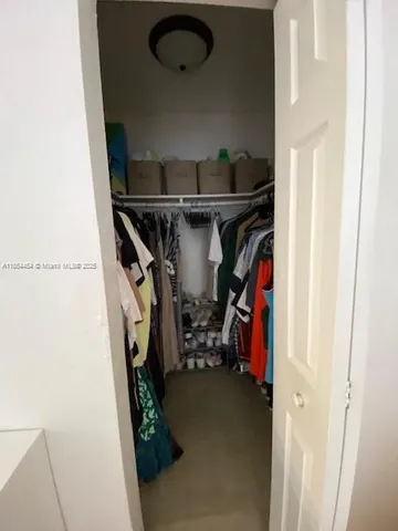 a view of walk in closet with clothes and shoes