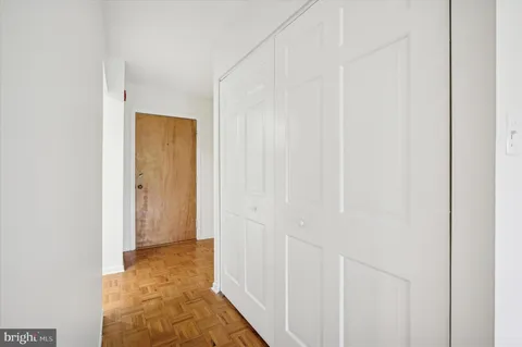 a view of a hallway with wooden floor and closet