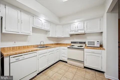 a kitchen with granite countertop a sink and white cabinets