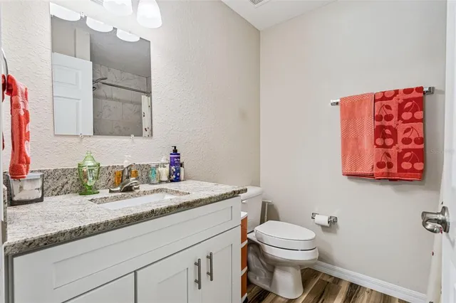 a bathroom with a granite countertop toilet sink and mirror