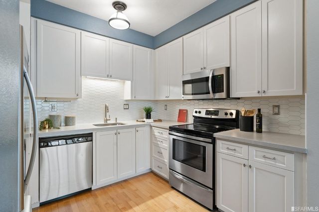 a kitchen with cabinets stainless steel appliances and a sink