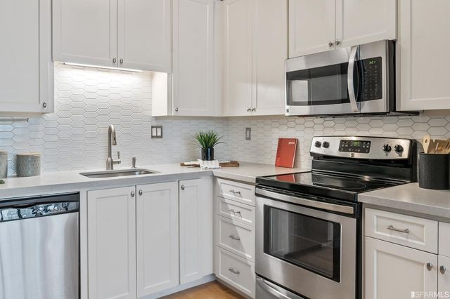a kitchen with granite countertop white cabinets stainless steel appliances and sink