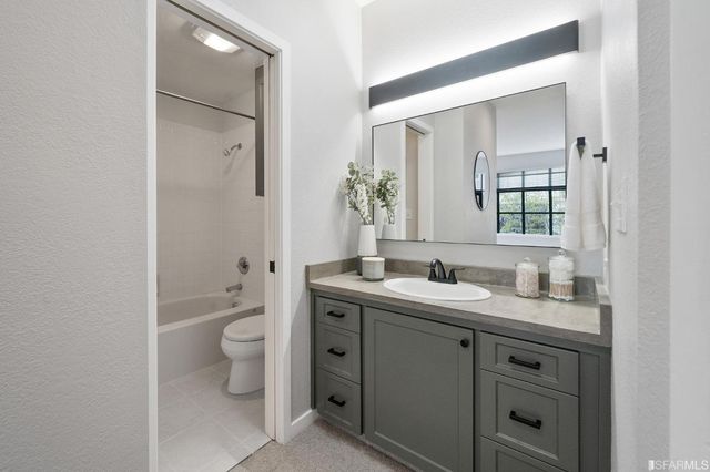 a bathroom with a granite countertop toilet sink and mirror