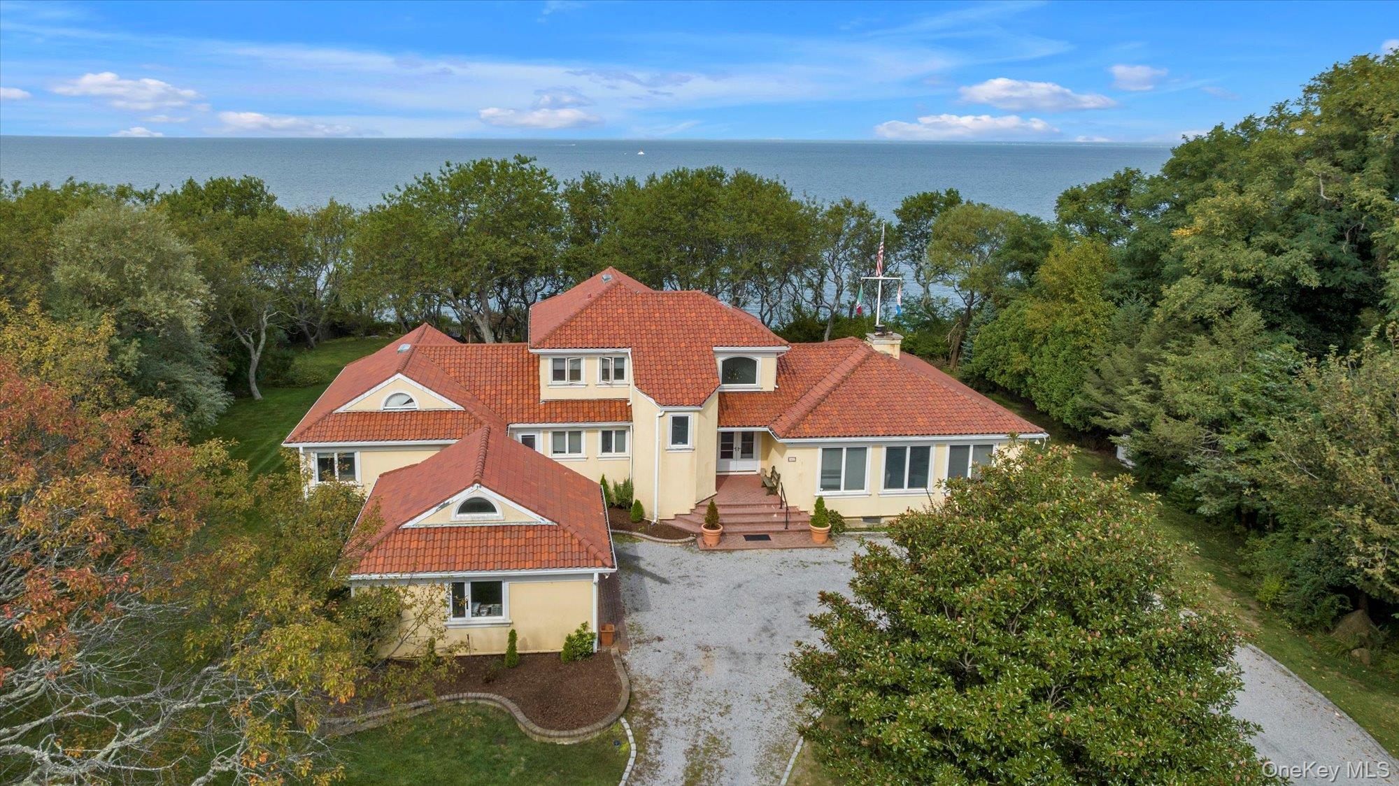 3400 Dignans Road Cutchogue, NY 11935 - Photo 48 of 50 View of front facade featuring a tiled roof, a water view, stucco siding, and a chimney