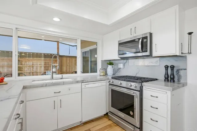 a kitchen with granite countertop white cabinets stainless steel appliances and sink