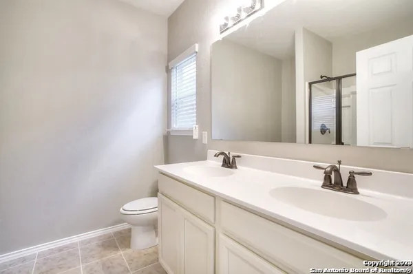 a bathroom with a toilet a sink a mirror and a window