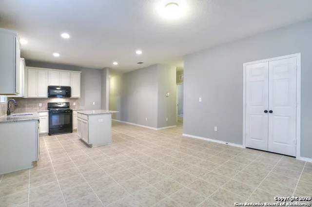 a view of a kitchen with a sink and dishwasher a refrigerator with white cabinets