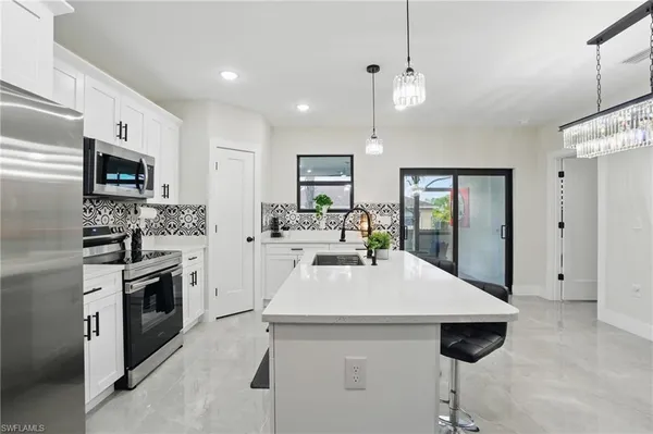 a kitchen with stainless steel appliances kitchen island granite countertop a table chairs and a refrigerator