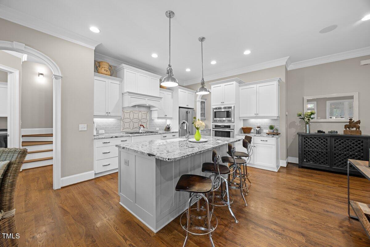 3034 Lewis Farm Road Raleigh, NC 27607 - Photo 18 of 60 a kitchen with stainless steel appliances kitchen island granite countertop a wooden floor and white cabinets
