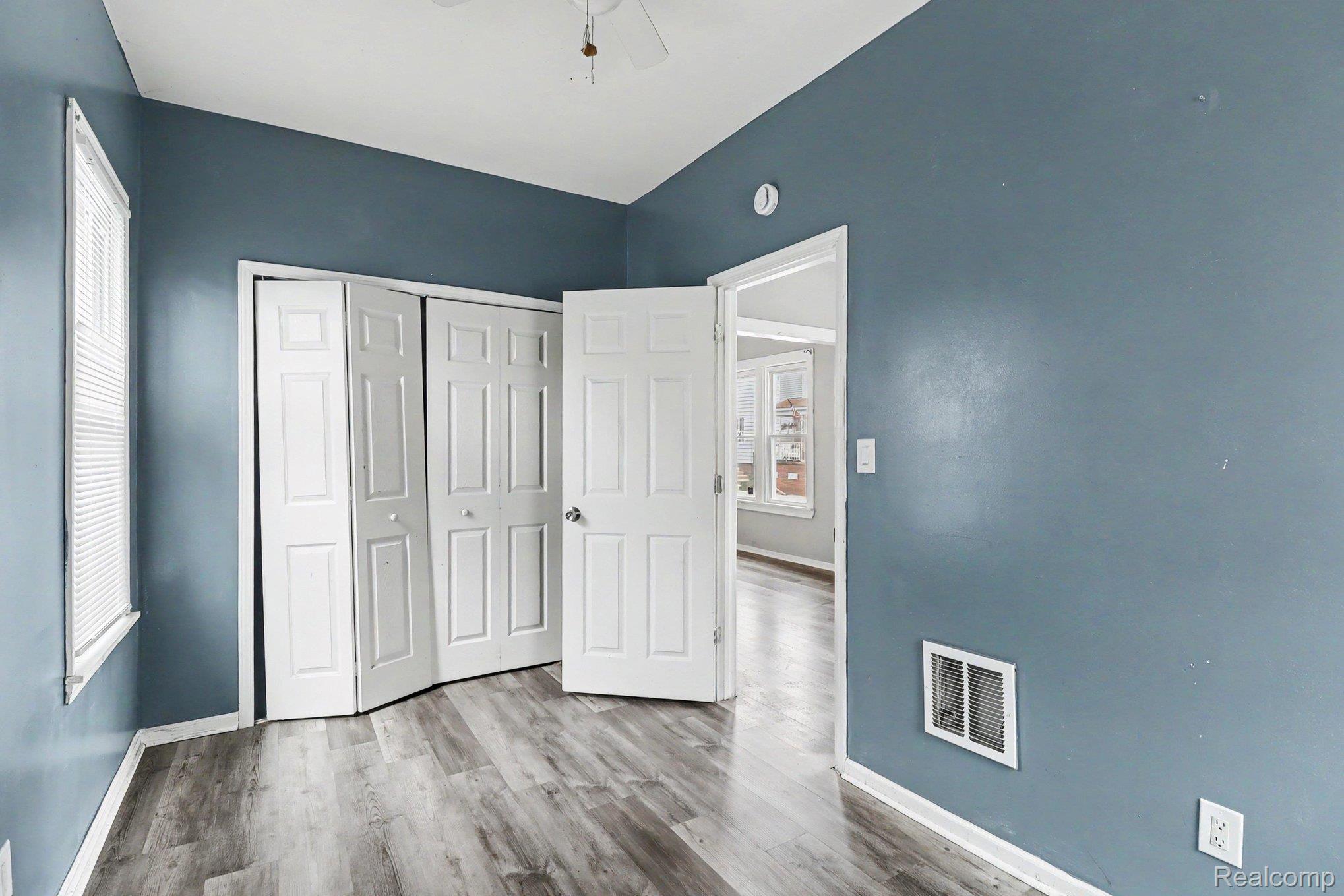 7743 Pitt Street Detroit, MI 48209 - Photo 12 of 15 Room featuring wood-finish flooring, a window with blinds, and white bi-fold closet doors