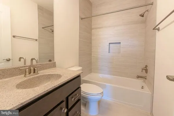 a bathroom with a granite countertop sink a toilet and shower