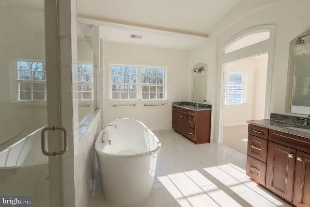 a spacious bathroom with a tub sink and mirror