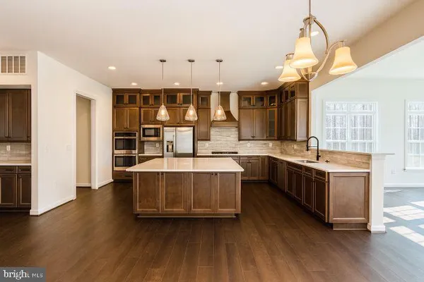 a kitchen with stainless steel appliances granite countertop a sink a stove and a wooden floors
