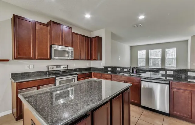 a kitchen with stainless steel appliances granite countertop a sink stove microwave and refrigerator