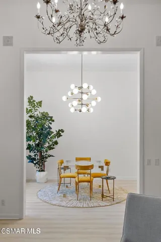 a dining room with wooden floor a chandelier a wooden table and chairs