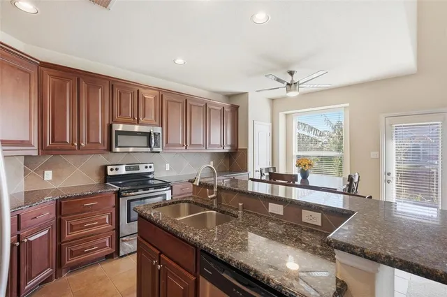 a kitchen with stainless steel appliances granite countertop wooden cabinets a stove top oven a sink and dishwasher