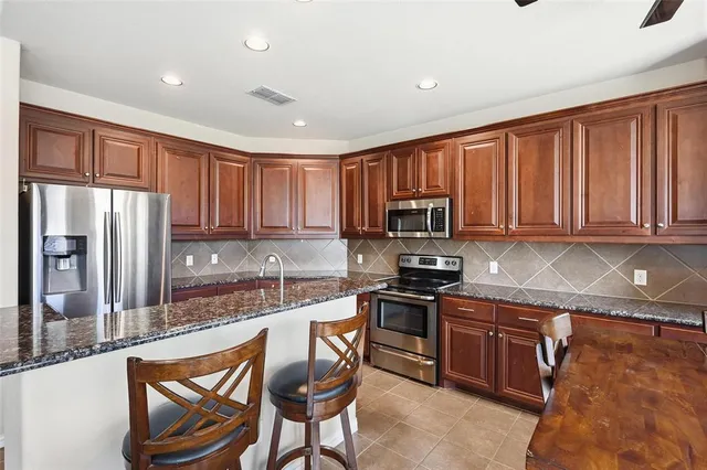 a kitchen with stainless steel appliances granite countertop a stove a sink and a microwave
