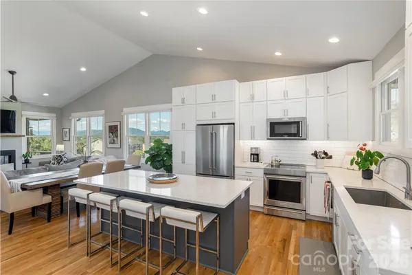 a kitchen with stainless steel appliances a stove a sink a microwave a center island and a refrigerator