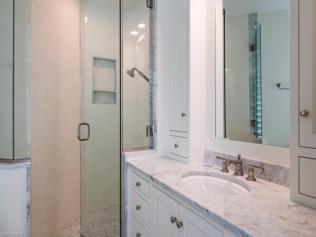 3630 Rum Row Naples, FL 34102 - Photo 20 of 28 a bathroom with a granite countertop sink a mirror and shower