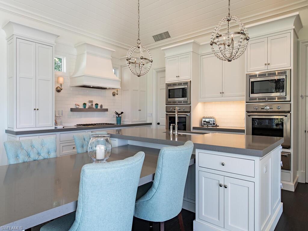 3630 Rum Row Naples, FL 34102 - Photo 6 of 28 a kitchen with stainless steel appliances granite countertop a sink a stove a microwave a refrigerator cabinets and living room view