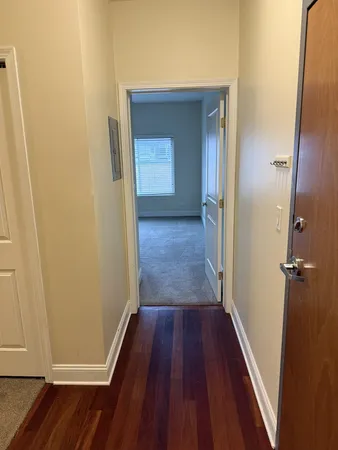 a view of a hallway with wooden floor and closet