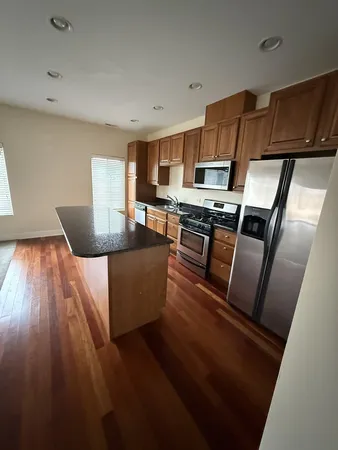 a living room with stainless steel appliances furniture and a kitchen view