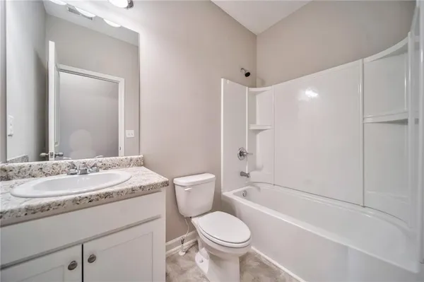 a bathroom with a granite countertop sink toilet mirror and bathtub