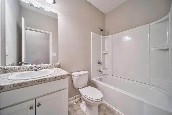 a bathroom with a granite countertop sink toilet mirror and bathtub
