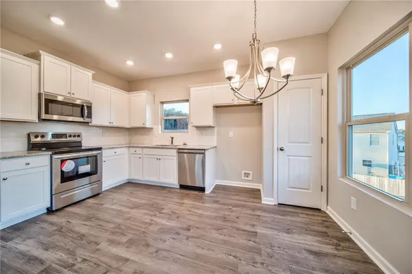 a kitchen with kitchen island granite countertop a stove a sink and a chandelier