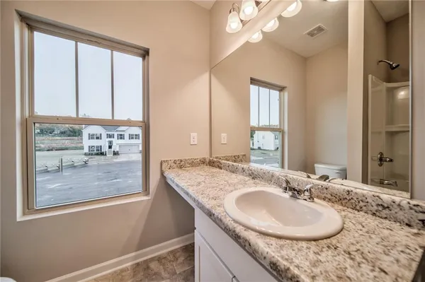 a bathroom with a granite countertop sink a mirror and a shower
