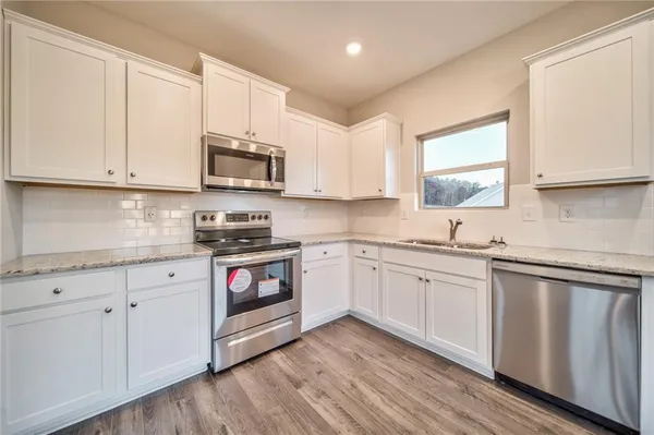 a kitchen with granite countertop white cabinets and white appliances
