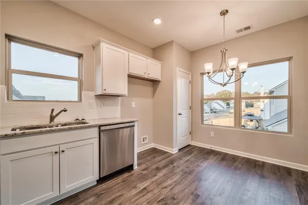 a kitchen with a sink dishwasher a stove and white cabinets with wooden floor