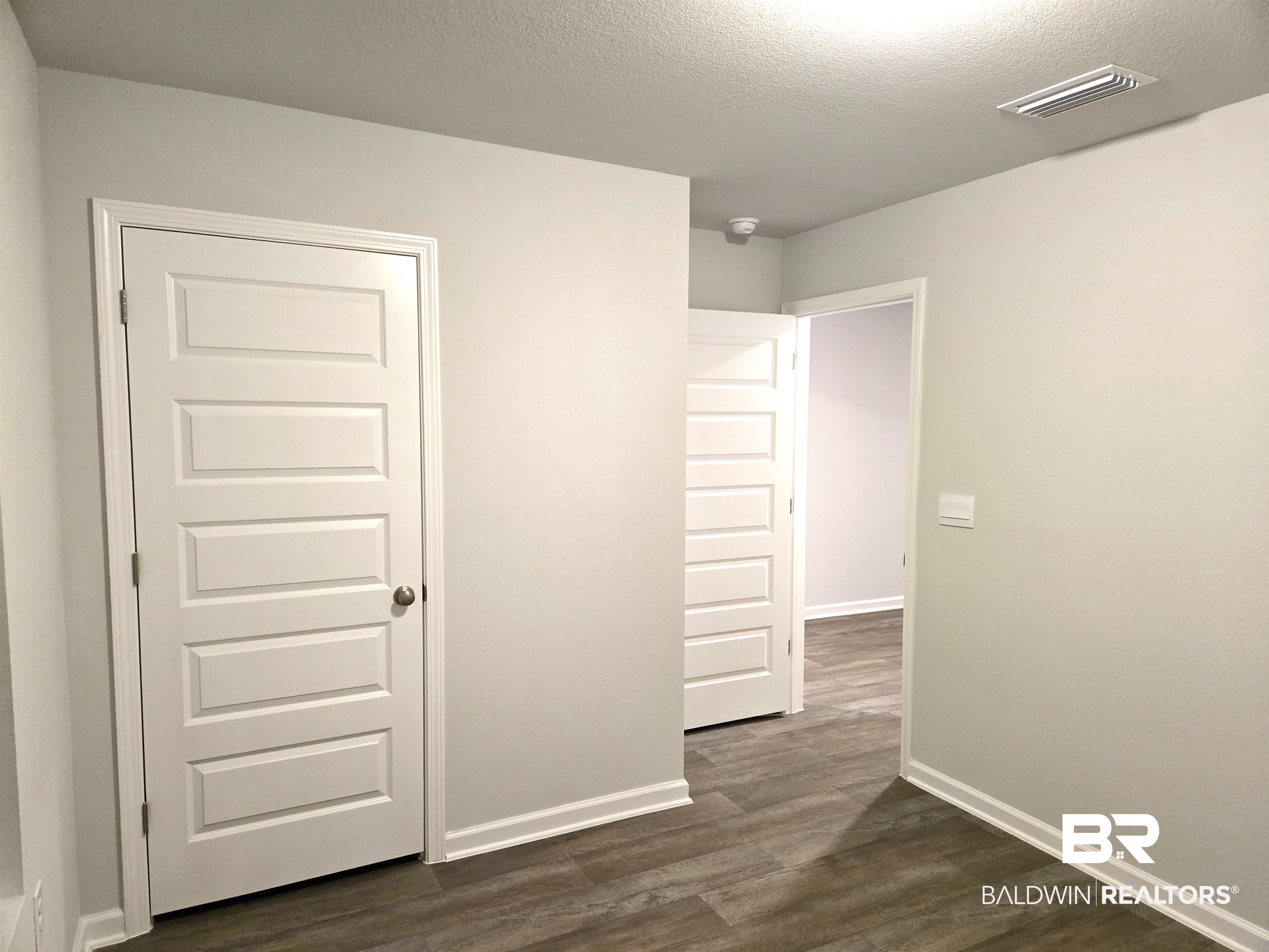 24227 Veranda Circle Elberta, AL 36530 - Photo 11 of 36 Unfurnished bedroom with dark hardwood / wood-style flooring, a closet, and a textured ceiling