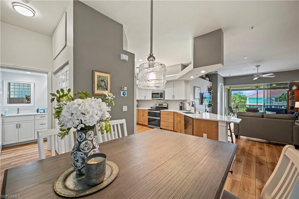 23810 Marbella Bay Road, Unit 203 Estero, FL 34135 - Photo 6 of 47 Dining area with sink, ceiling fan, a towering ceiling, and light wood-type flooring