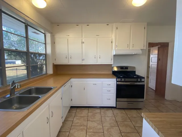 a kitchen with granite countertop a sink stove and cabinets