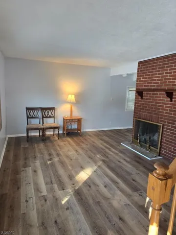 a view of empty room with fireplace and wooden floor