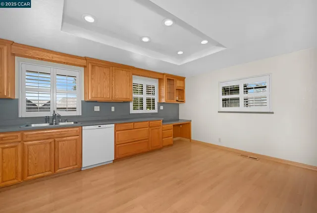 a kitchen with stainless steel appliances granite countertop a sink and cabinets with wooden floor