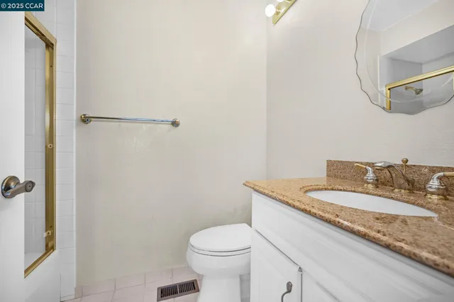a bathroom with a granite countertop sink a toilet and a mirror