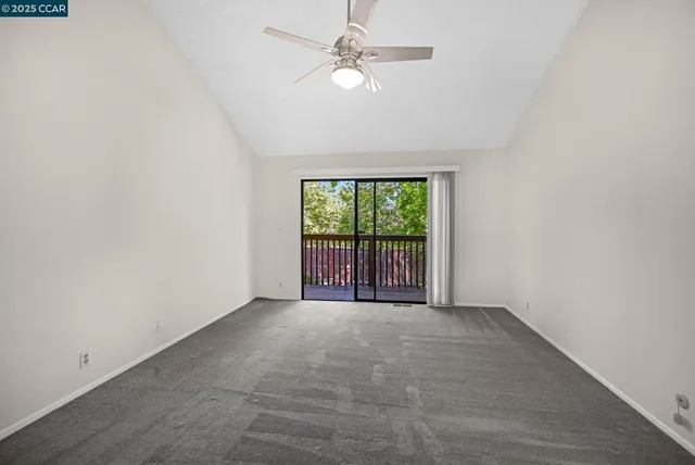 an empty room with windows and ceiling fan