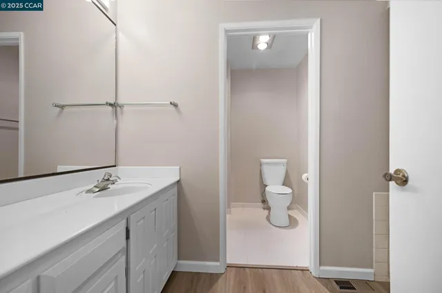 a bathroom with a granite countertop sink a toilet and a mirror