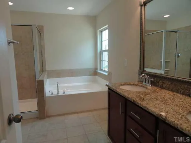 a bathroom with a granite countertop sink a mirror and a bathtub