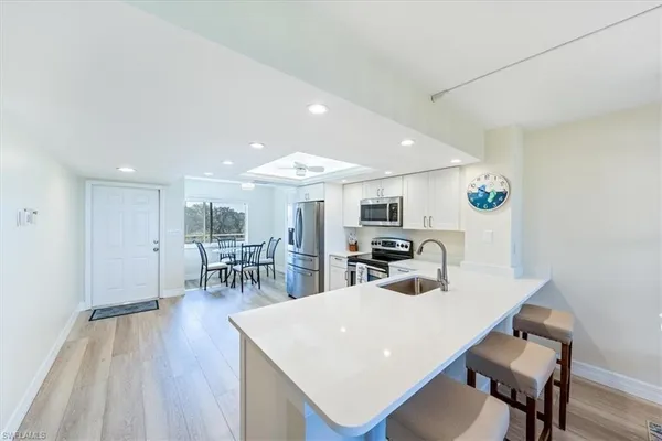 a kitchen with stainless steel appliances a dining table chairs and a refrigerator