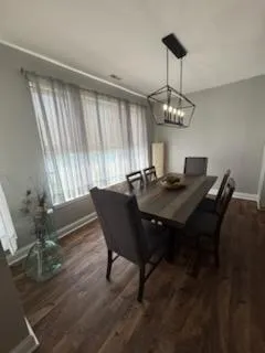 a dining room with wooden floor a chandelier a wooden table and chairs