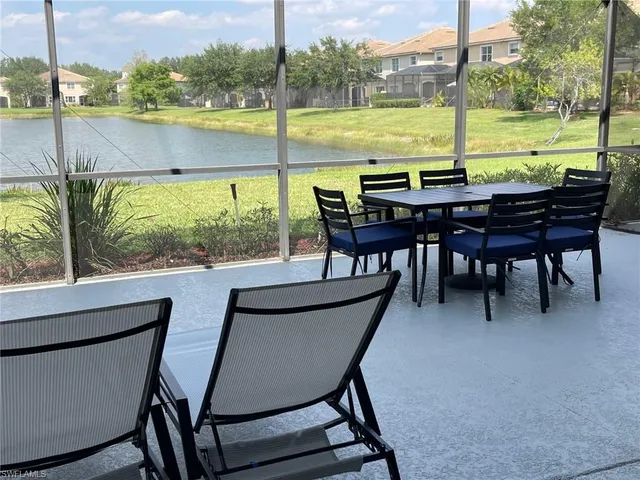 a view of an ocean from a dining room with a table and chairs