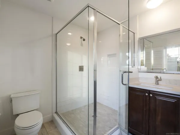 a bathroom with a granite countertop sink a toilet and shower